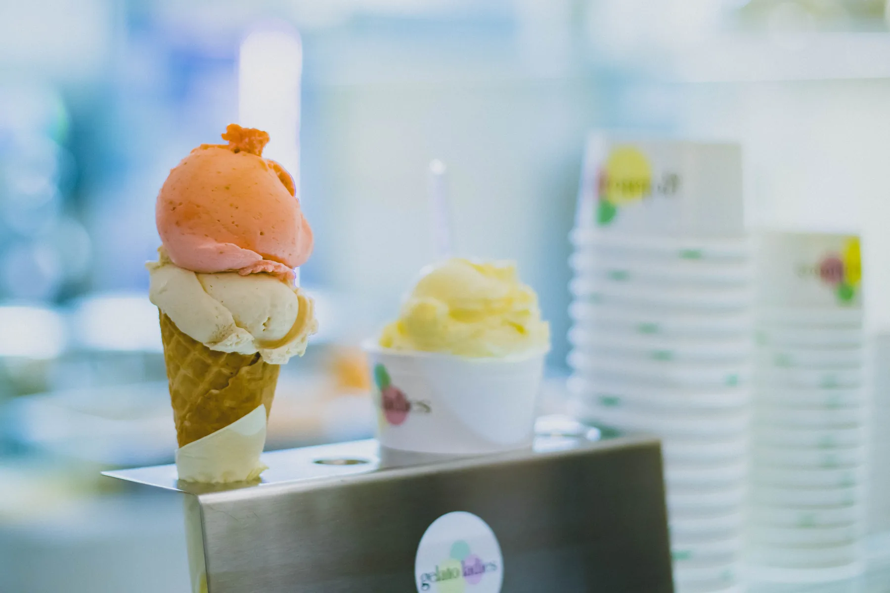Gelato cone held in front of a gelato display